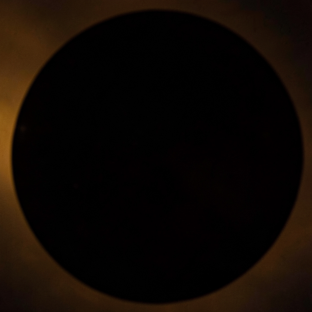 A dark circular image evoking community advocacy, warm amber tones against a shadowed background